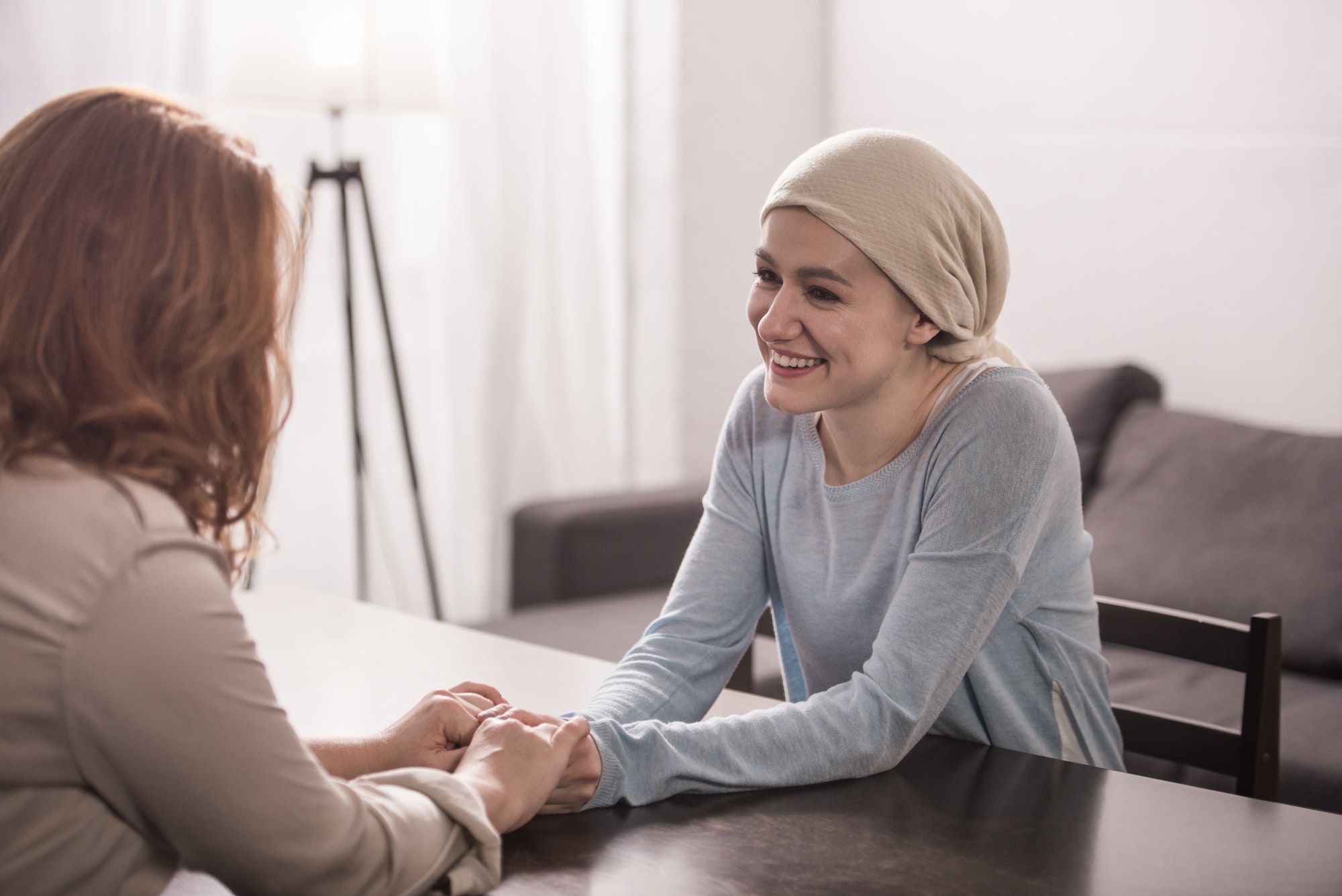 mother and sick adult daughter in kerchief holding hands and looking at each other